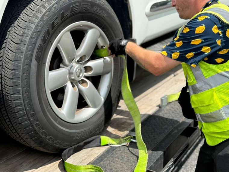 Close-up of a wheel strap locking a customer vehicle to the trailer deck